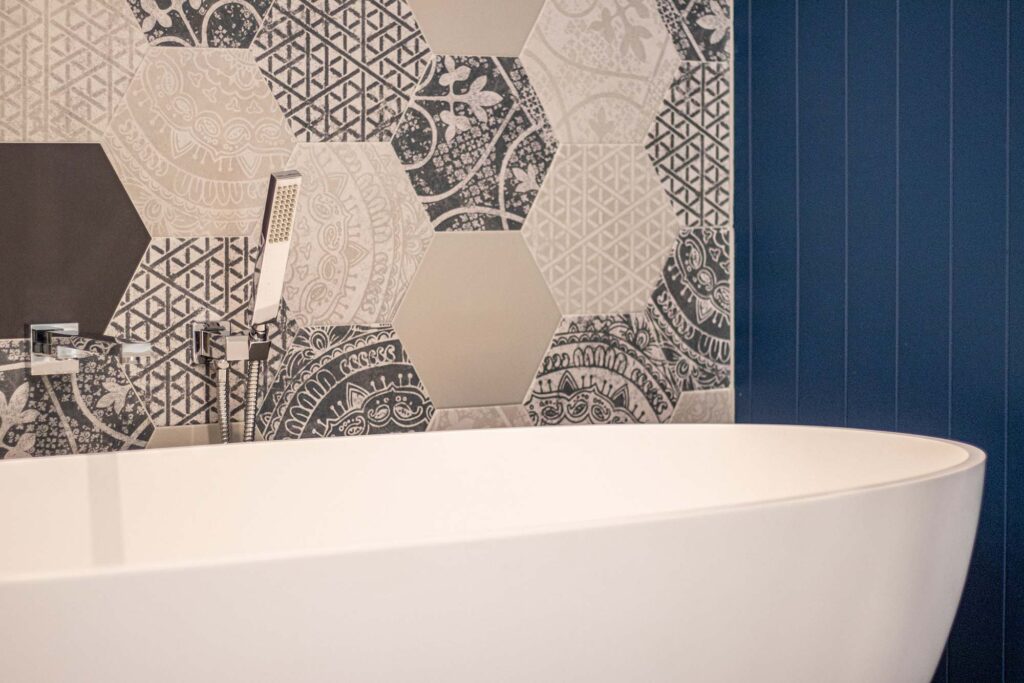 Blue toned hexagon tiles with an interesting pattern as a feature wall behind a free standing bathtub. This energy efficient renovation in Perth is showcasing some inspirational interior design.