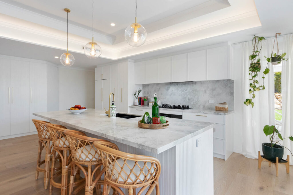 A beautiful coffered ceiling over a modern white kitchen boasting an island and stone bench tops. This energy efficient renovation in Perth, is inspirational.