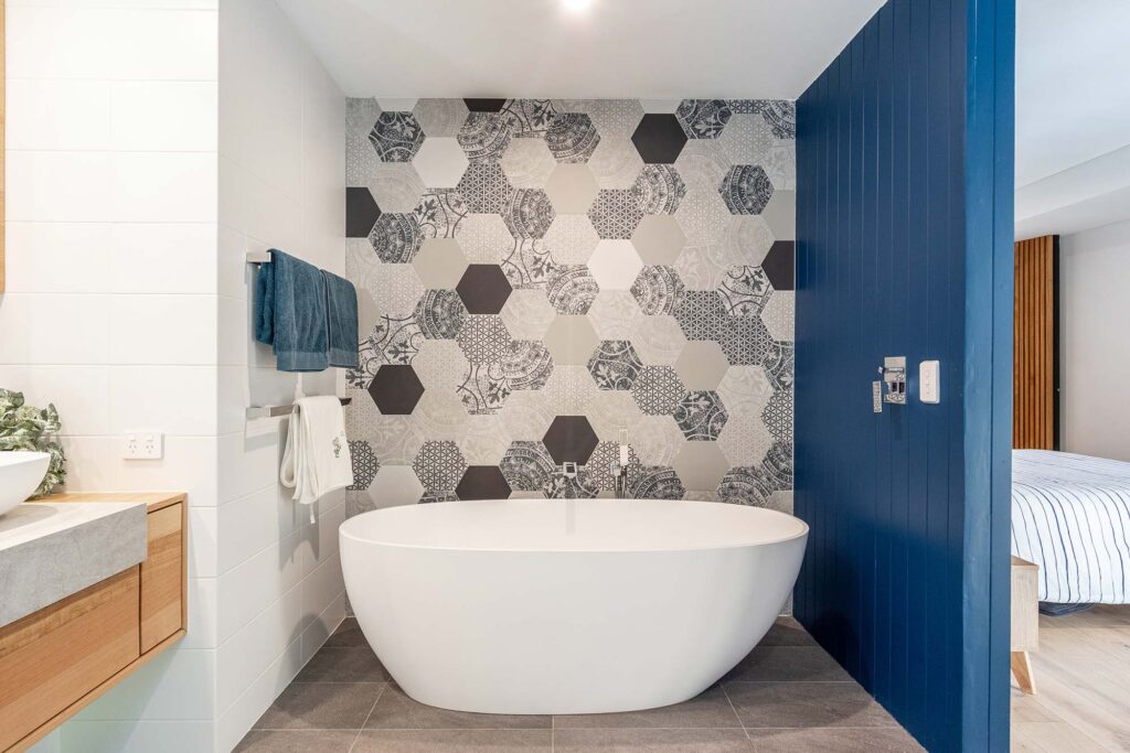 A freestanding bat tube with a hexagon tiled feature wall in a newly built energy efficient home in Perth.