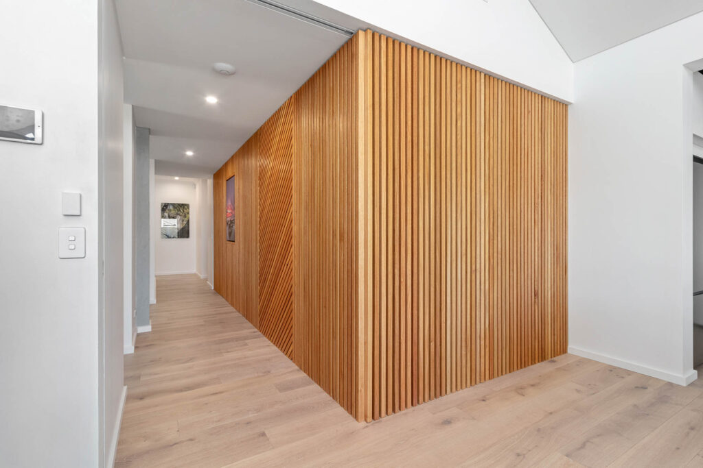 A timber clad hallway feature wall, a unique aspect of this sustainable home designed by an architect in Perth, and built by Eco Homes Group.
