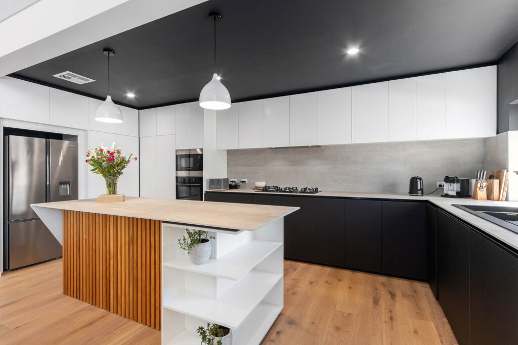A timber clad island combined with black and white cabinetry, this unique kitchen is a highlight in the recently finished sustainable home by Eco Homes Group.