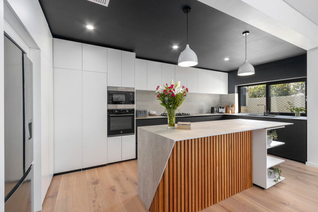 A timber clad island in a black and white kitchen, a unique feature in this sustainable Perth home build.